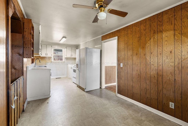 kitchen with backsplash, white appliances, ceiling fan, wooden walls, and white cabinets