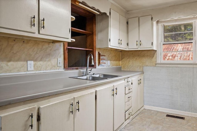 kitchen with white cabinets, crown molding, and sink