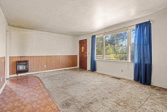 unfurnished living room featuring heating unit and wooden walls