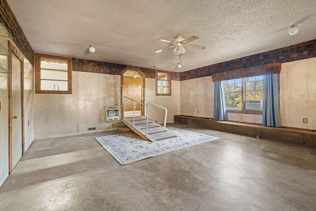 basement with ceiling fan, cooling unit, a textured ceiling, and heating unit