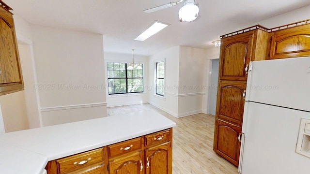 1704 Sharon Ln, Jasper, AL 35504 - kitchen with brown cabinetry, freestanding refrigerator, light wood-style floors, light countertops, and ceiling fan with notable chandelier