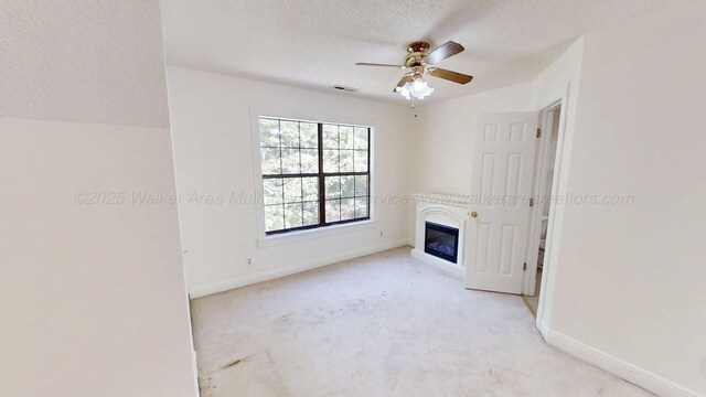 1704 Sharon Ln, Jasper, AL 35504 - unfurnished living room featuring visible vents, a glass covered fireplace, ceiling fan, a textured ceiling, and carpet flooring