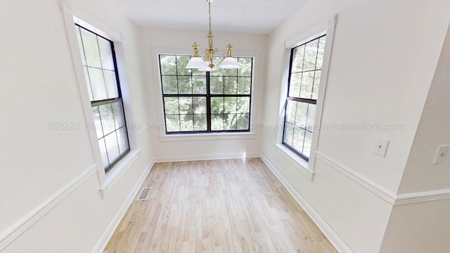 1704 Sharon Ln, Jasper, AL 35504 - unfurnished dining area with baseboards, a notable chandelier, a wealth of natural light, and light wood-style floors