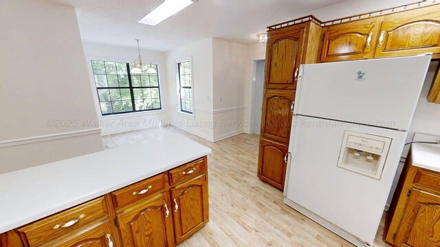 1704 Sharon Ln, Jasper, AL 35504 - kitchen with brown cabinetry, pendant lighting, white refrigerator with ice dispenser, light countertops, and light wood finished floors