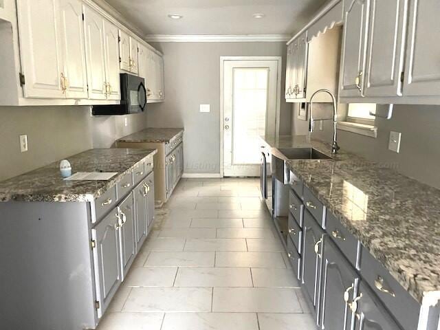 kitchen with crown molding, a sink, dark stone counters, and black microwave