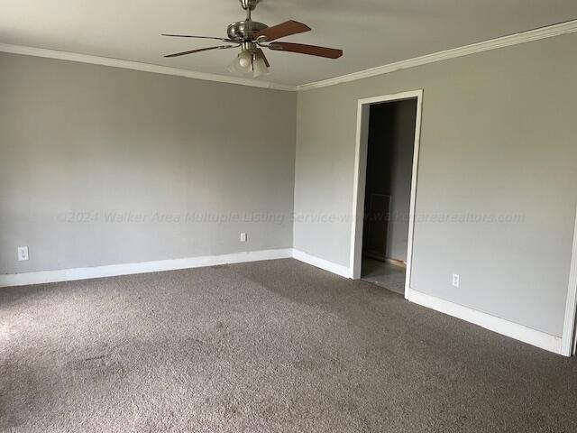 unfurnished room with crown molding, a ceiling fan, baseboards, and dark colored carpet