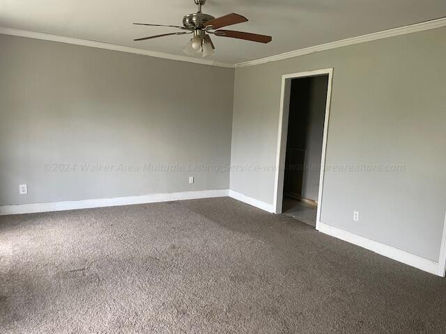 unfurnished room with crown molding, a ceiling fan, baseboards, and dark carpet