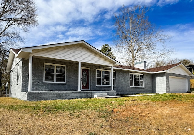 view of front of property featuring a chimney, brick siding, a front yard, and an attached garage
