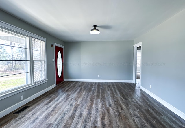 spare room featuring baseboards, visible vents, and dark wood-style flooring