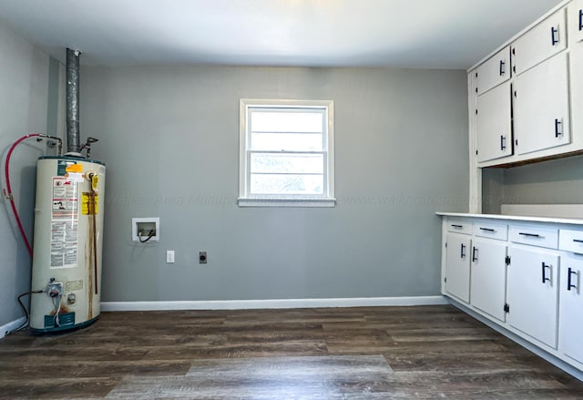 clothes washing area featuring electric dryer hookup, gas water heater, dark wood-style floors, baseboards, and cabinet space