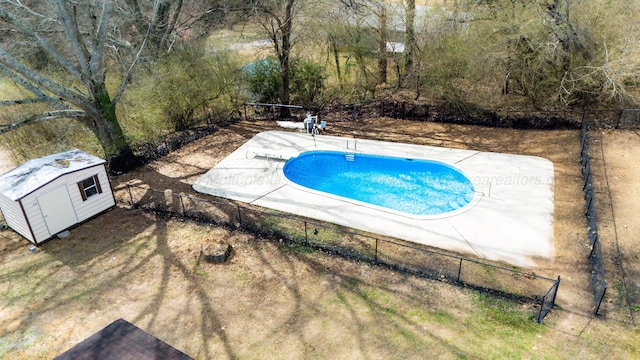 view of swimming pool featuring a storage unit, an outdoor structure, fence, and a fenced in pool