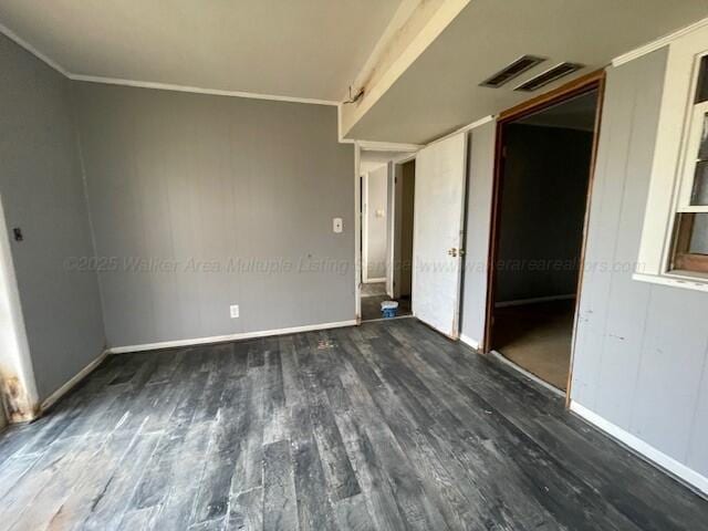 empty room featuring baseboards, visible vents, crown molding, and wood finished floors