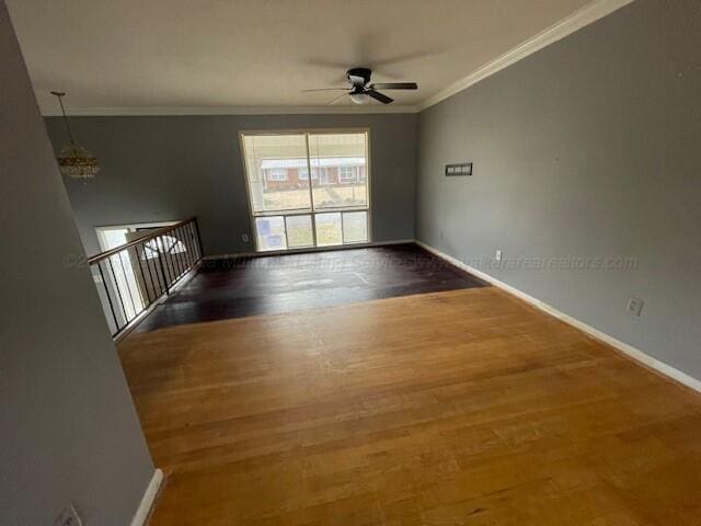 unfurnished room featuring crown molding, baseboards, wood finished floors, and ceiling fan with notable chandelier