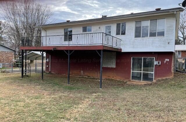 rear view of house featuring a deck, a yard, and a carport