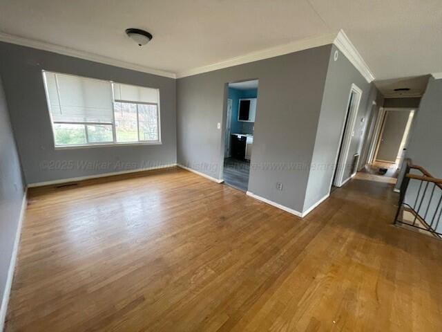 unfurnished room with baseboards, crown molding, and wood finished floors
