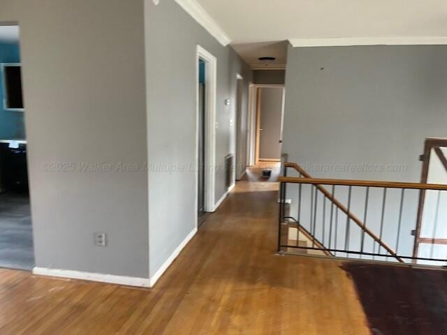 hall with ornamental molding, an upstairs landing, baseboards, and wood finished floors