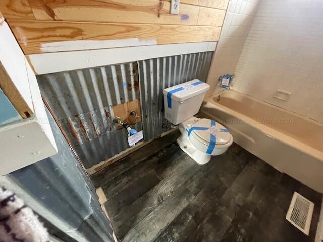 bathroom featuring shower / tub combination, visible vents, toilet, and wood finished floors