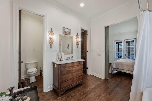 ensuite bathroom featuring toilet, ornamental molding, wood finished floors, and baseboards