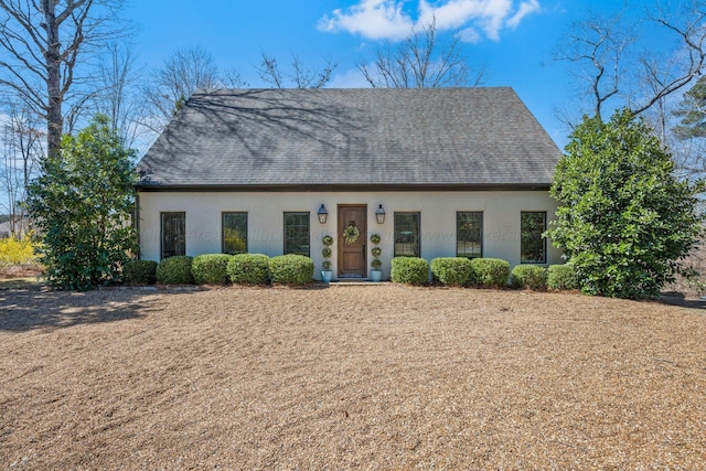 cape cod house featuring a shingled roof and stucco siding