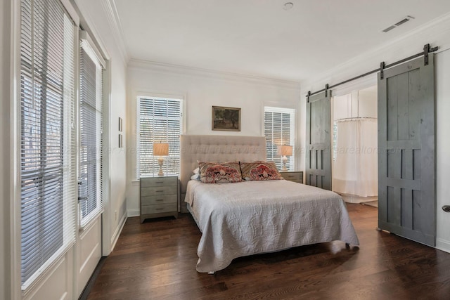 bedroom with visible vents, dark wood finished floors, ornamental molding, and a barn door