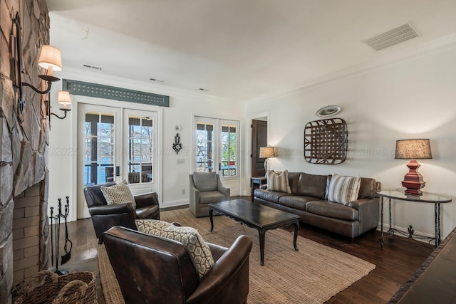 living area with wood finished floors, visible vents, ornamental molding, and french doors