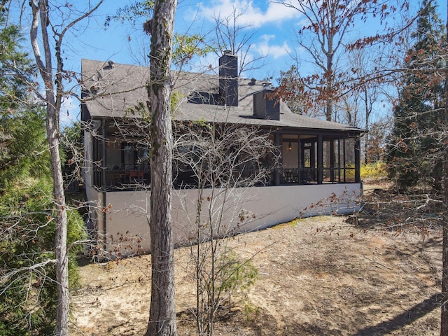 rear view of property with a chimney, a sunroom, and roof with shingles