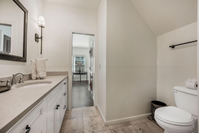bathroom with baseboards, vaulted ceiling, vanity, and toilet