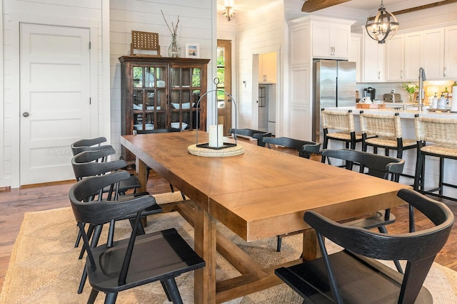 dining space with an inviting chandelier, wooden walls, and light hardwood / wood-style flooring