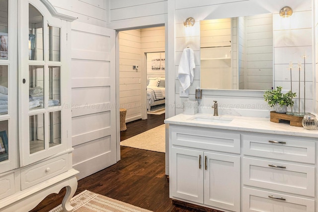 bathroom featuring wooden walls, hardwood / wood-style floors, and vanity