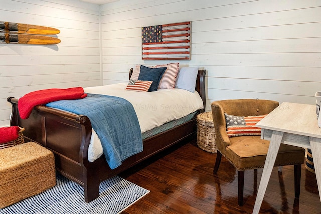 bedroom featuring dark wood-type flooring and wooden walls