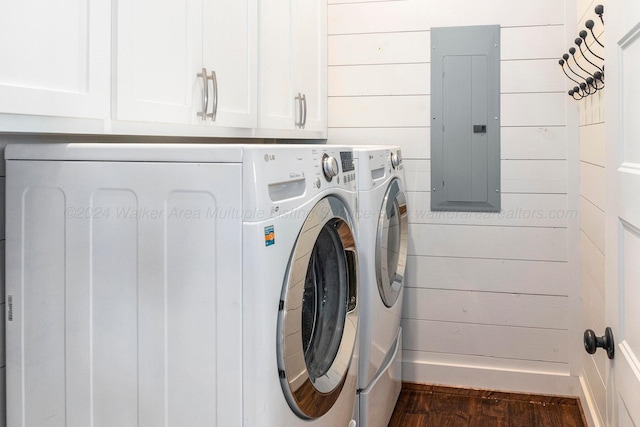 laundry area featuring cabinets, wooden walls, dark wood-type flooring, washing machine and clothes dryer, and electric panel