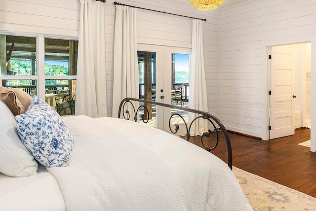 bedroom with access to outside, dark hardwood / wood-style flooring, wooden walls, and french doors