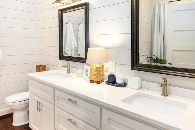 bathroom featuring wooden walls, vanity, wood-type flooring, and toilet