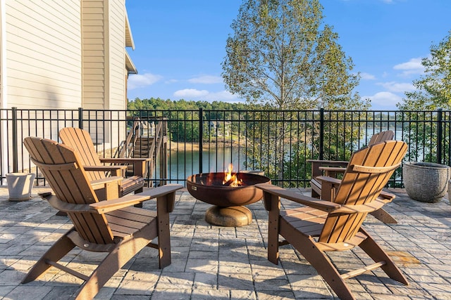 balcony with a water view, an outdoor fire pit, and a patio area