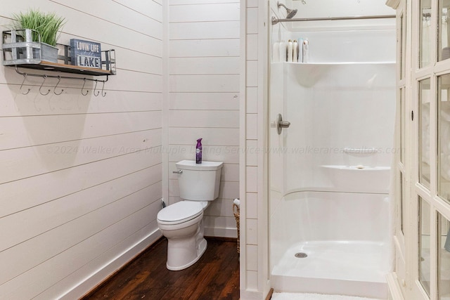 bathroom with walk in shower, wooden walls, toilet, and hardwood / wood-style flooring