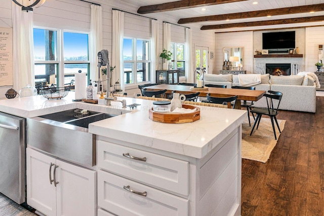 kitchen with white cabinetry, dishwasher, light stone countertops, dark hardwood / wood-style flooring, and a center island with sink