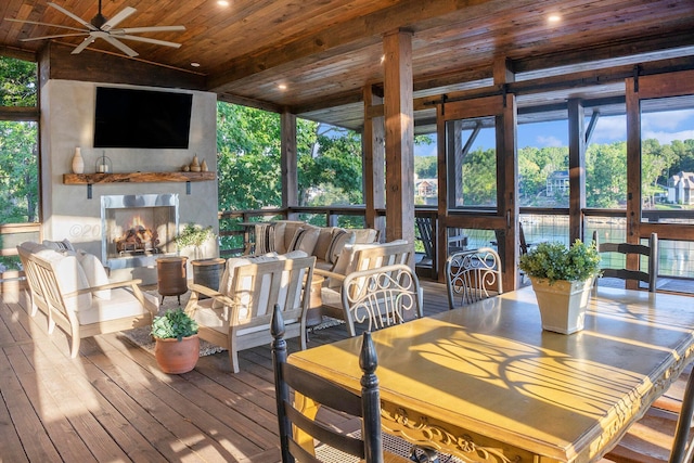 sunroom / solarium featuring a large fireplace, plenty of natural light, ceiling fan, and wooden ceiling