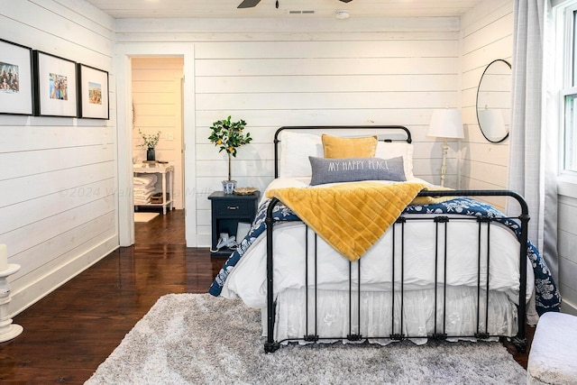 bedroom with wooden walls and dark wood-type flooring