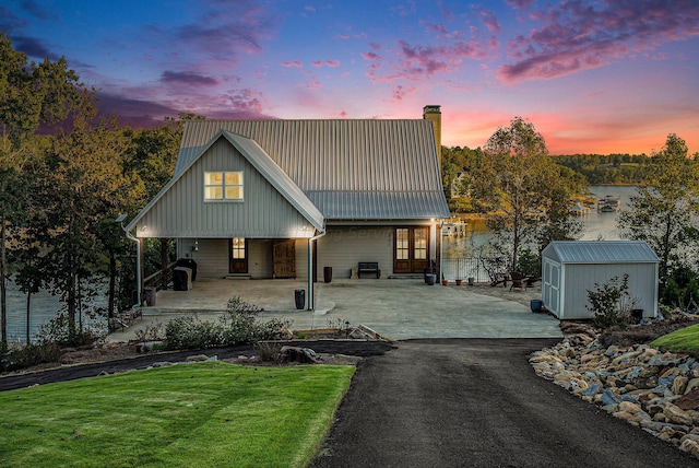 view of front of home featuring a yard, a water view, a porch, and a storage shed