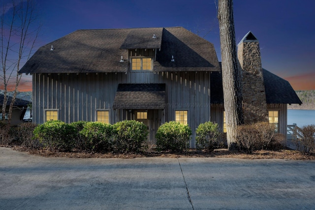 view of side of home with roof with shingles, board and batten siding, and a chimney