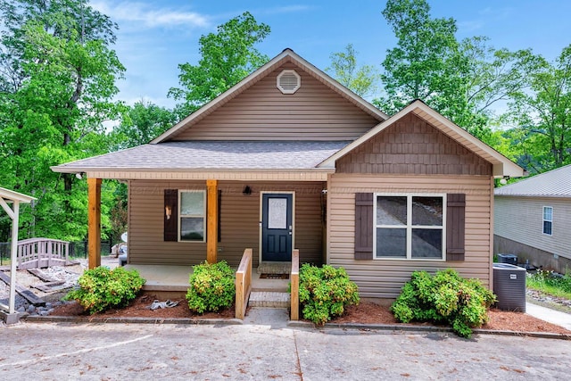 bungalow-style home featuring central AC unit, a shingled roof, and a porch