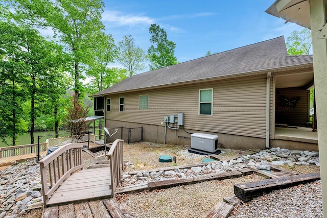 rear view of property featuring fence and a shingled roof