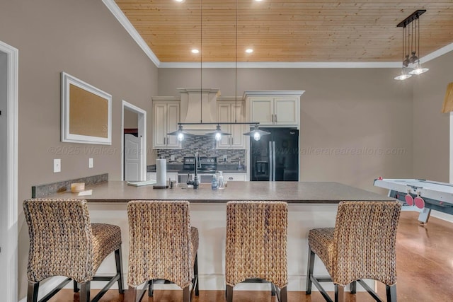 kitchen with fridge, black fridge, a breakfast bar area, tasteful backsplash, and wood ceiling