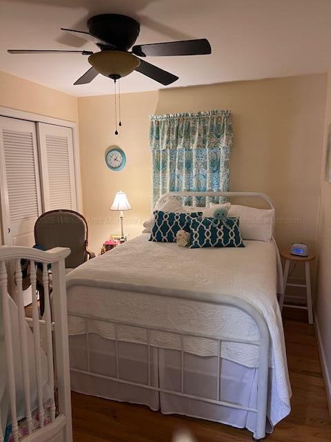 bedroom featuring ceiling fan, baseboards, wood finished floors, and a closet