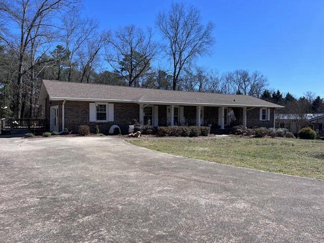 single story home featuring a porch and a front lawn