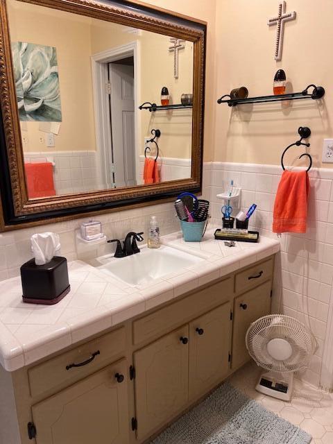 bathroom with tile walls, tile patterned floors, a wainscoted wall, and vanity
