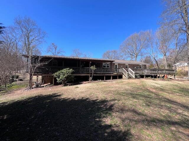 rear view of house featuring a wooden deck and a yard