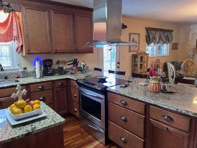 kitchen with light stone counters, wood finished floors, island range hood, a sink, and stainless steel electric range