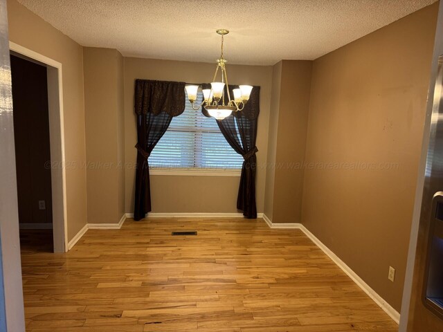 4407 Pineywoods Sipsey Rd, Jasper, AL 35504 - unfurnished dining area with light wood-style flooring, a chandelier, a textured ceiling, and baseboards