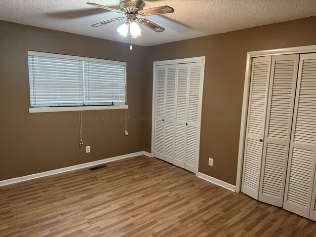 4407 Pineywoods Sipsey Rd, Jasper, AL 35504 - unfurnished bedroom featuring two closets, light wood-style flooring, baseboards, a textured ceiling, and ceiling fan